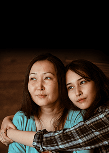 Una hija abrazando a su madre mientras miran a lo lejos