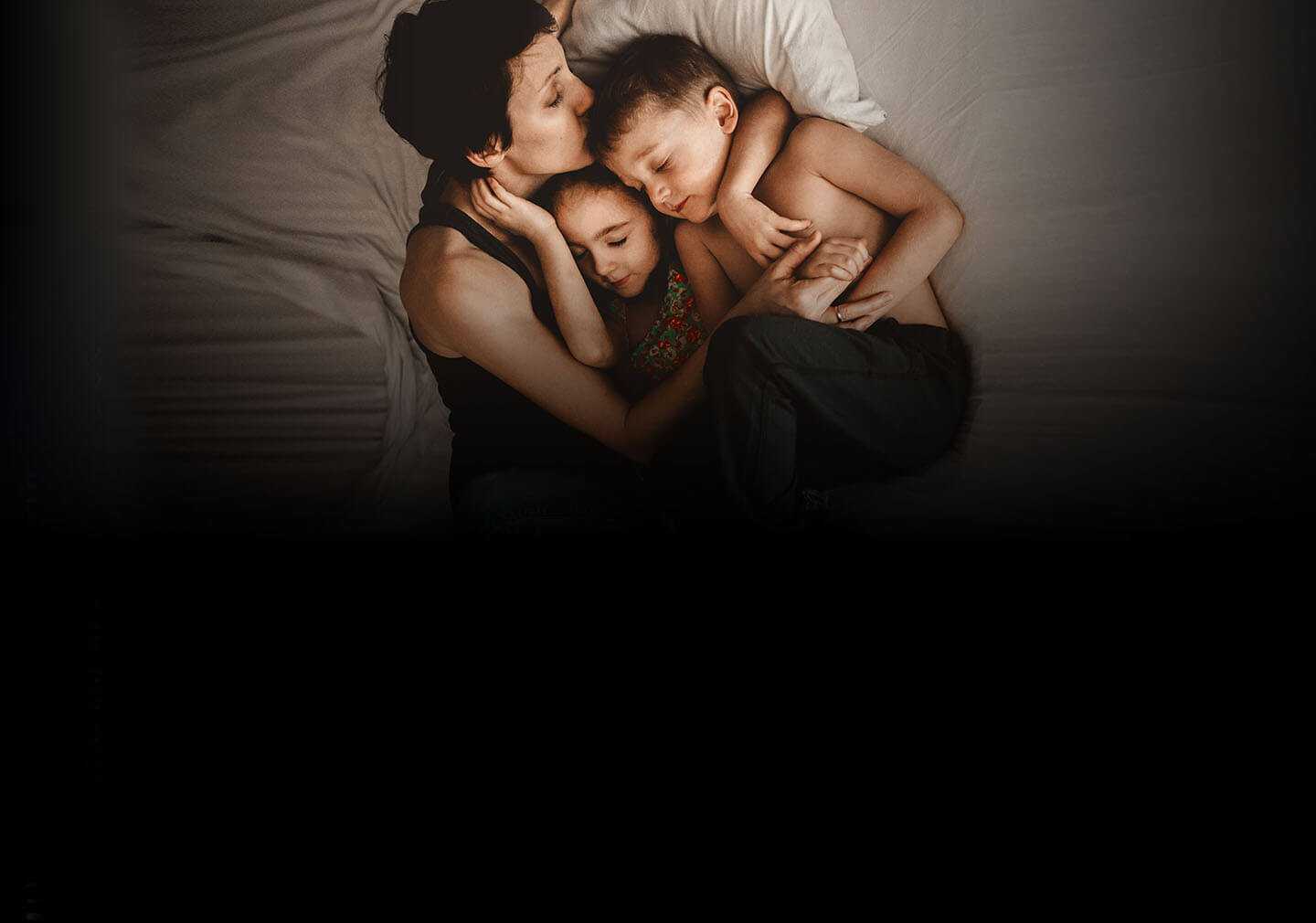 Mamá abrazando su hijo y su hija en la cama